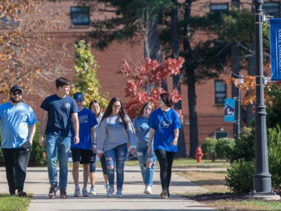 A group of seven students walk across the 91ɫ campus.