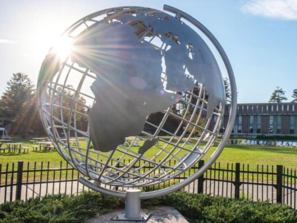 A metal globe sculpture sits in the middle of the 91ɫ campus green.