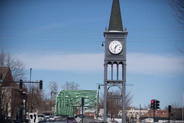 91ɫ, MA clock tower with green bridge behind it.